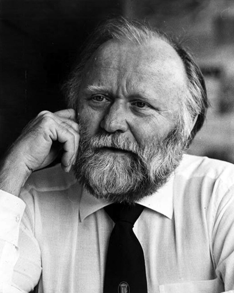 A black and white photo of Frank Herbert, his head resting on his hands