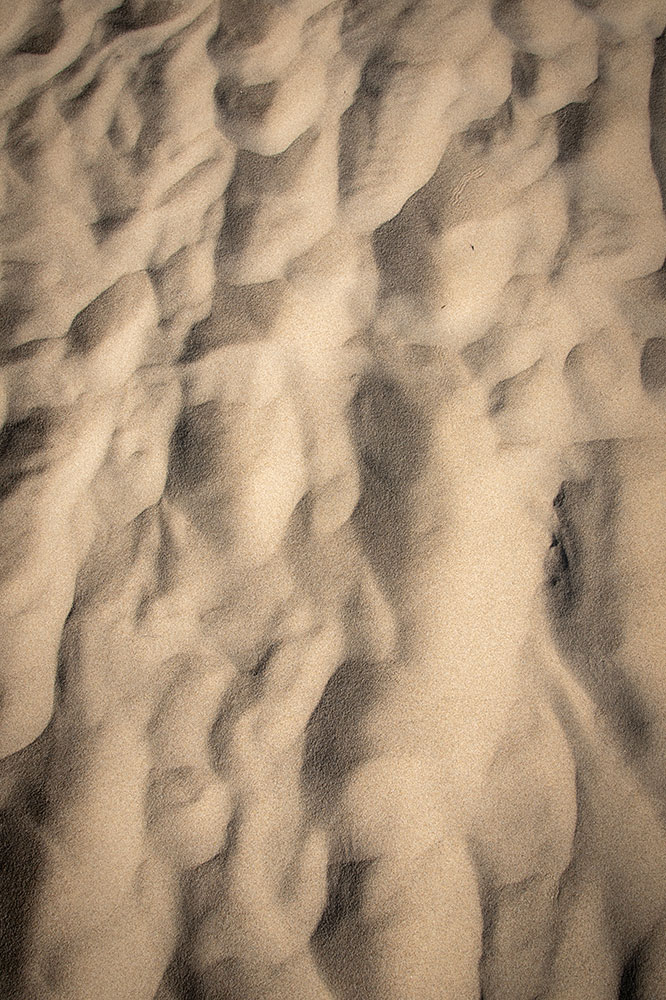 A close-up, overhead view shows waves and undulations in the sands