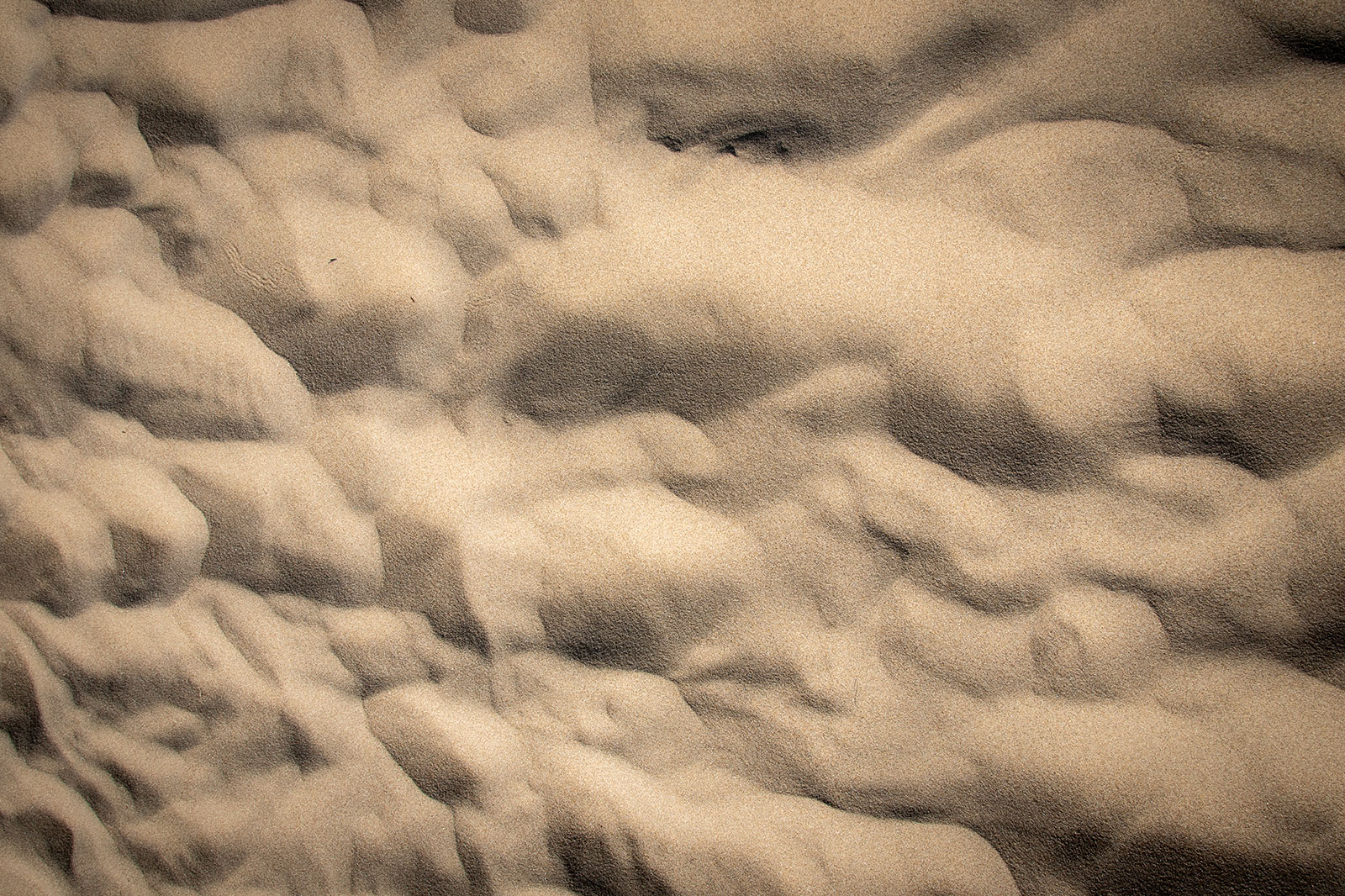 A close-up, overhead view shows waves and undulations in the sands