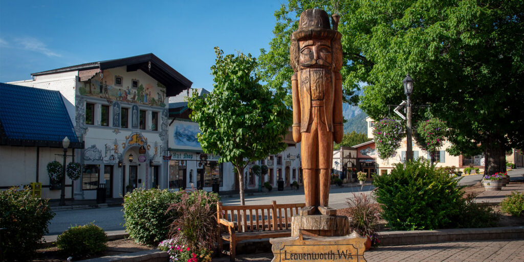 A large wooden statue of a nutcracker stands atop a sign that says: Leavenworth, Washington, The Bavarian Village