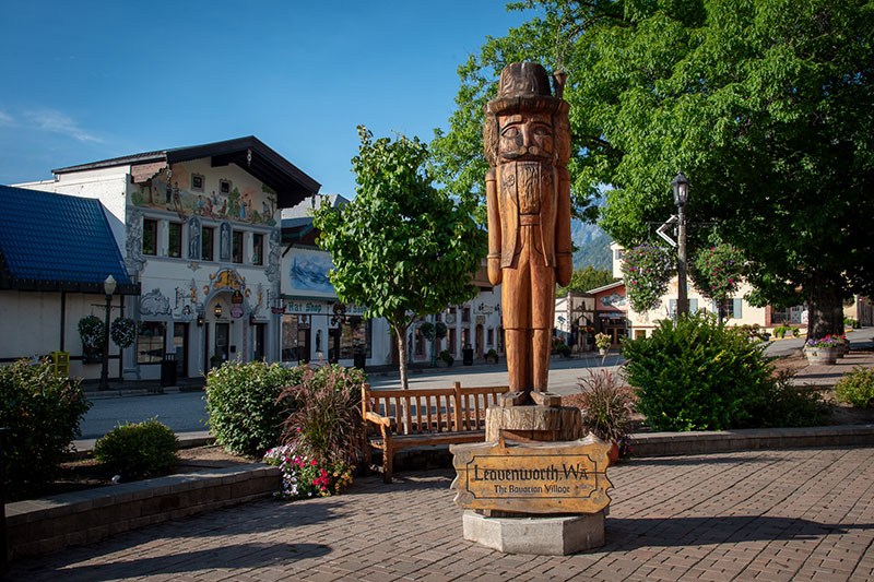 A large wooden statue of a nutcracker stands atop a sign that says: Leavenworth, Washington, The Bavarian Village