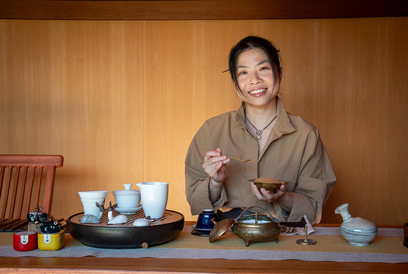 Liu smiles while preparing the incense bowl for the tea service. Beside her is a full set of tea ware laid out to start the the ceremony.